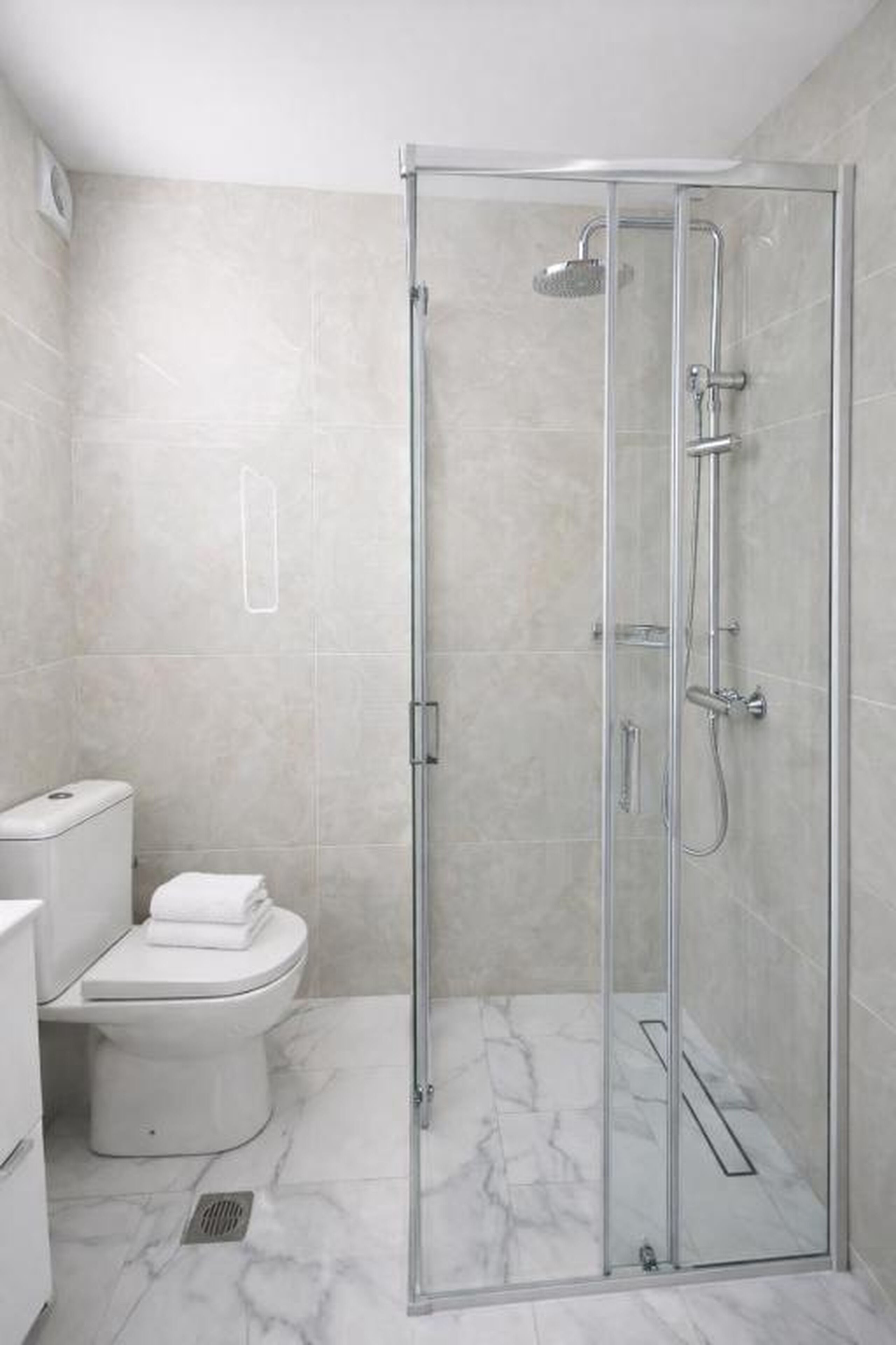 Ein modernes Badezimmer mit einer Glaskabine zur Dusche, einer Toilette und einem Bidet.