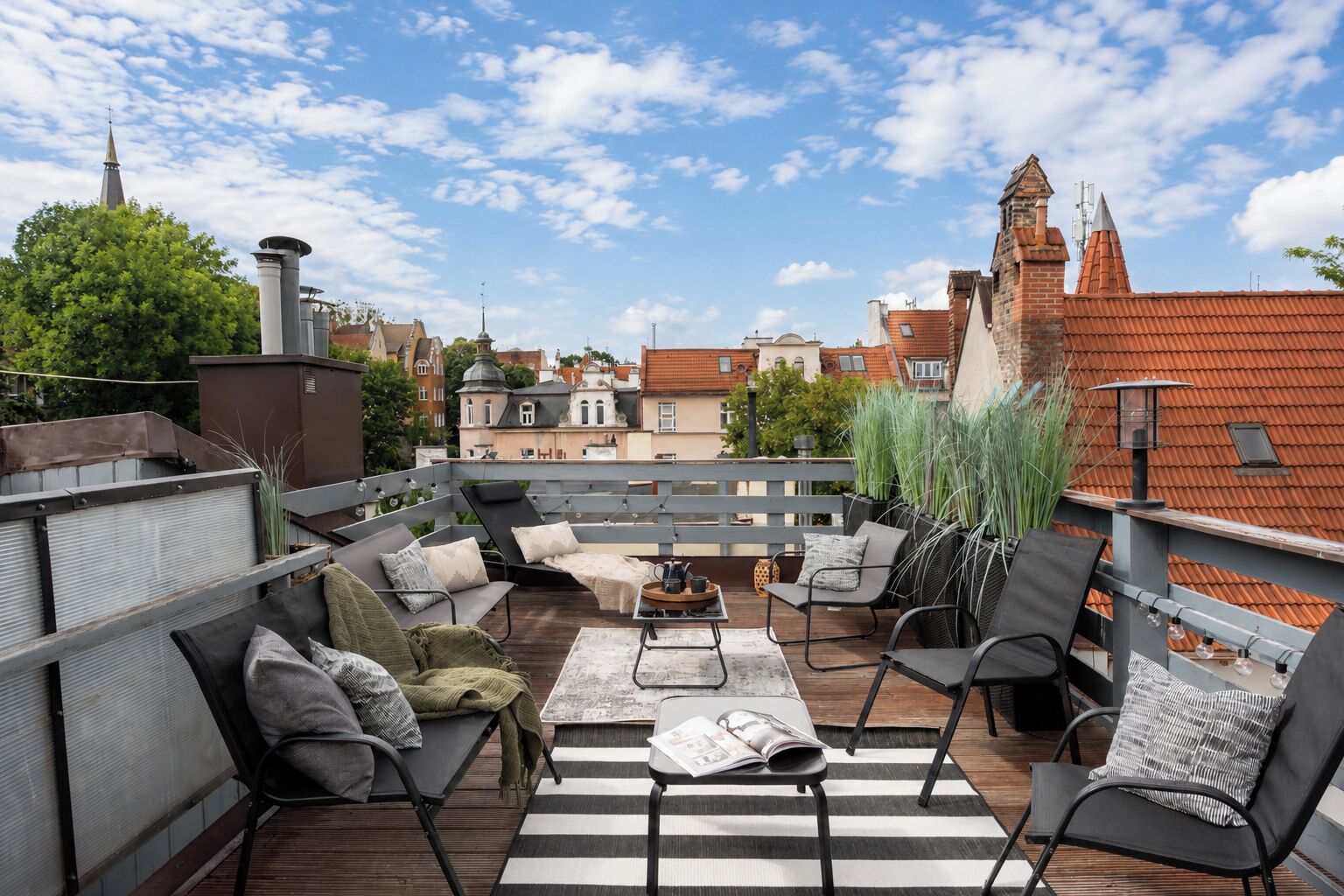 A rooftop terrace with outdoor seating, a view of the cityscape, and a brick chimney.