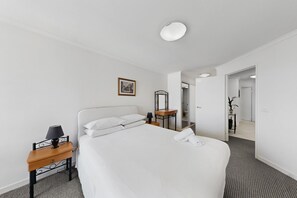 Ein Hotelzimmer mit einem großen Bett, einem Nachttisch mit Lampe, einem Spiegel und einem gerahmten Bild an der Wand.