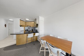 Une cuisine moderne avec un îlot central, des chaises blanches et une table à manger.