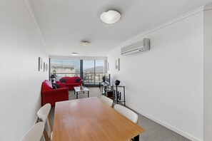 Une chambre moderne avec une table en bois, un canapé rouge et un balcon offrant une vue agréable.
