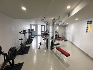 Ein Fitnessstudio mit Laufbändern, Gewichten und einer Sitzbank.