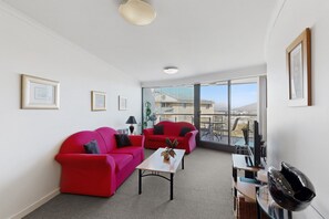 Un salon moderne avec deux canapés rouges, une petite table et un balcon offrant une vue agréable.