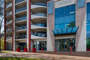 A multi-story building with a commercial unit on the ground floor, large windows, and a distinctive red and white color scheme. - Top Floor Braddon | Sunset Views to Black Mountain (Braddon)