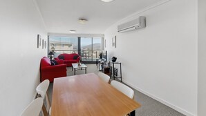 Quarto moderno com mesa de madeira, sofá vermelho e varanda com vista.