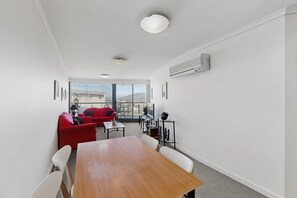 Ein modernes Zimmer mit einem Holztisch, einem roten Sofa und einem Balkon mit Blick.
