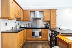 Eine moderne Küche mit Holzschränken, Edelstahlgeräten und einem eingebauten Backofen.