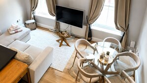 En moderne stue med et fladskærms-tv, en sofa, et sofabord og et spiseområde med stole.