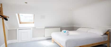 A bedroom with a bed, a window, a radiator, and a wooden wardrobe.