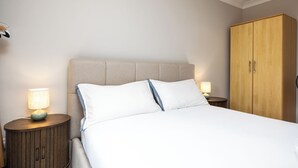 Et hotelværelse med en seng, to sengeborde med lamper og en træskab.
