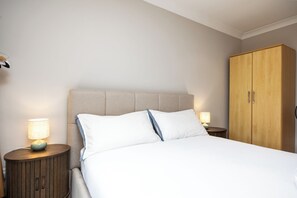 Ein Hotelzimmer mit einem Bett, zwei Nachttischen mit Lampen und einem Holzschrank.