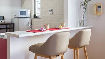 A modern kitchen with a white countertop, red cabinets, and two bar stools.
