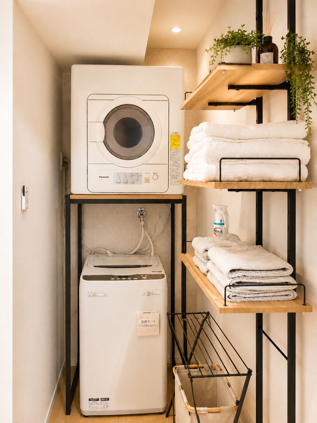 A compact laundry area with a washing machine, dryer, and shelves for towels.