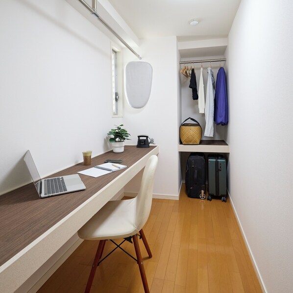 A compact room with a desk, chair, laptop, and a small potted plant.