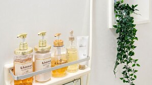 A bathroom with a shower, a mirror, and a shelf with toiletries.