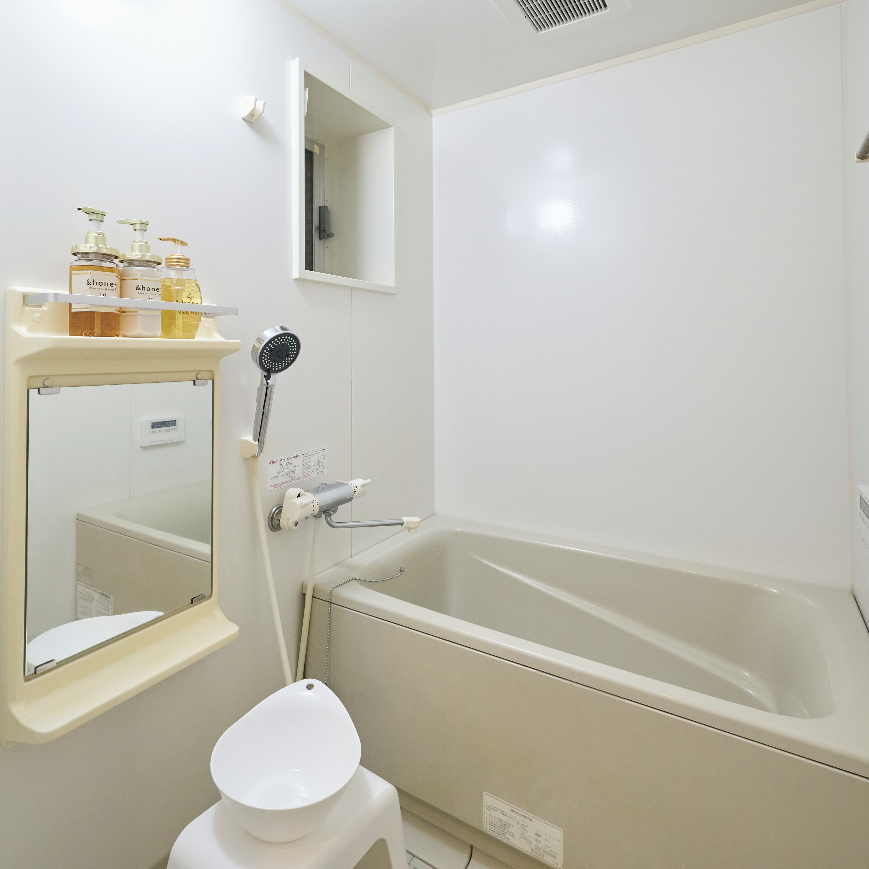 Ein Badezimmer mit einer Badewanne, einer Toilette, einem Spiegel und einem Ablagefach mit Toilettenartikeln.