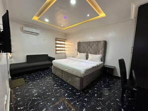 Ein Schlafzimmer mit einem Bett, einem Sofa, einem Fernseher und einer Deckenleuchte.