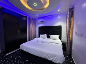 A hotel room with a large bed, dark-toned wardrobe, and a modern ceiling design. - 4 Bedroom Presidential Apartment (Lagos)