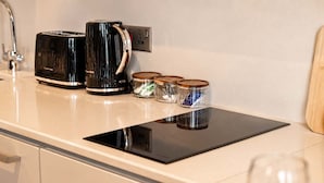 Una encimera de cocina con un tostador, una cafetera y tres frascos de vidrio con tapa.