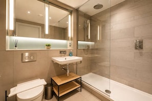 A modern bathroom with a glass-enclosed shower, a white sink, and a toilet. - Modern Studio by Stay With Us (Salford)