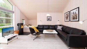 Una sala moderna con un sofá modular, una mesita, un televisor y una chimenea.