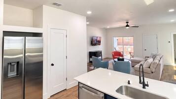 A modern kitchen with a built-in dishwasher, a stainless steel refrigerator, and a white countertop.