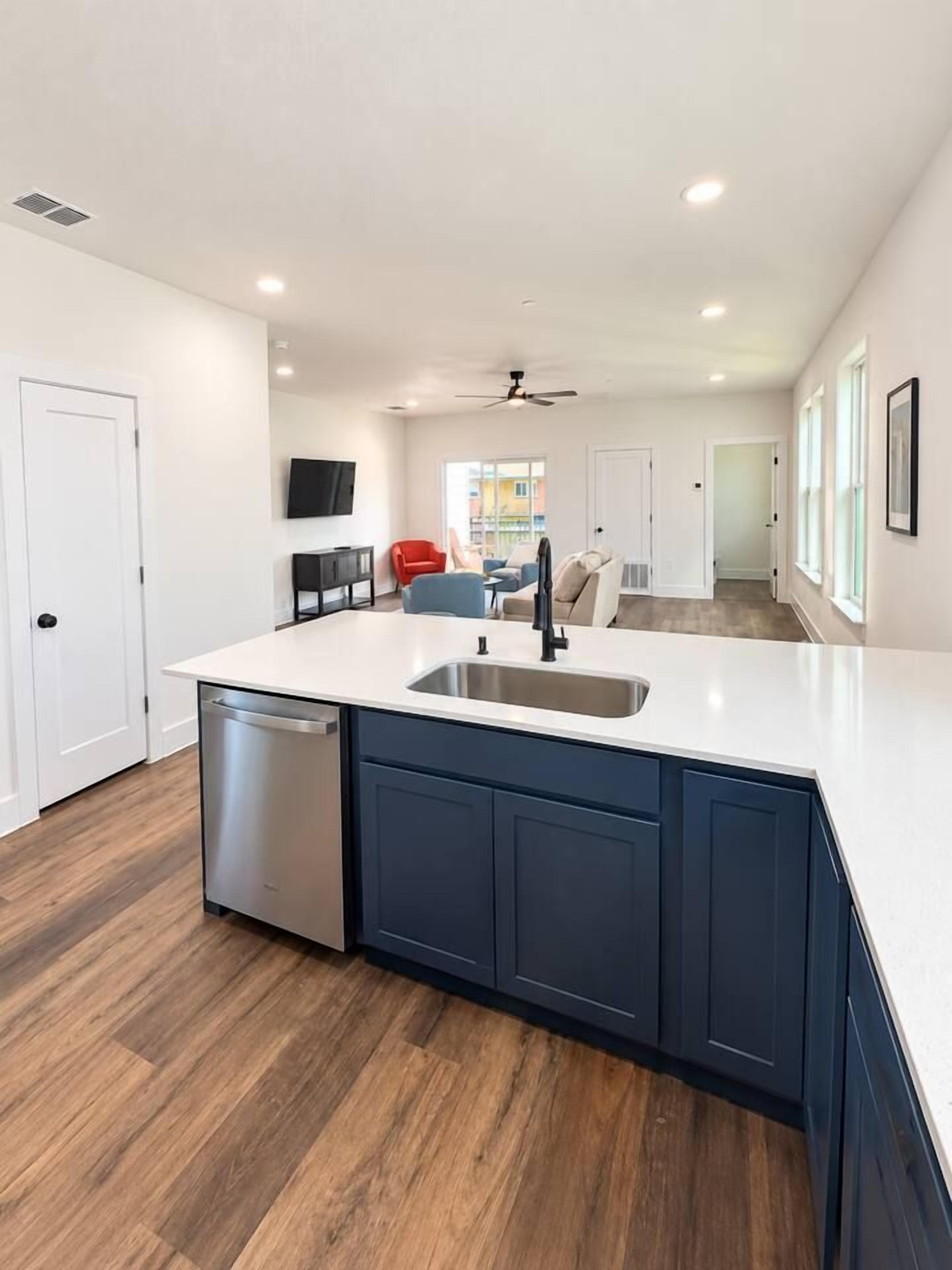 A modern kitchen with a dishwasher, a sink, and a ceiling fan.