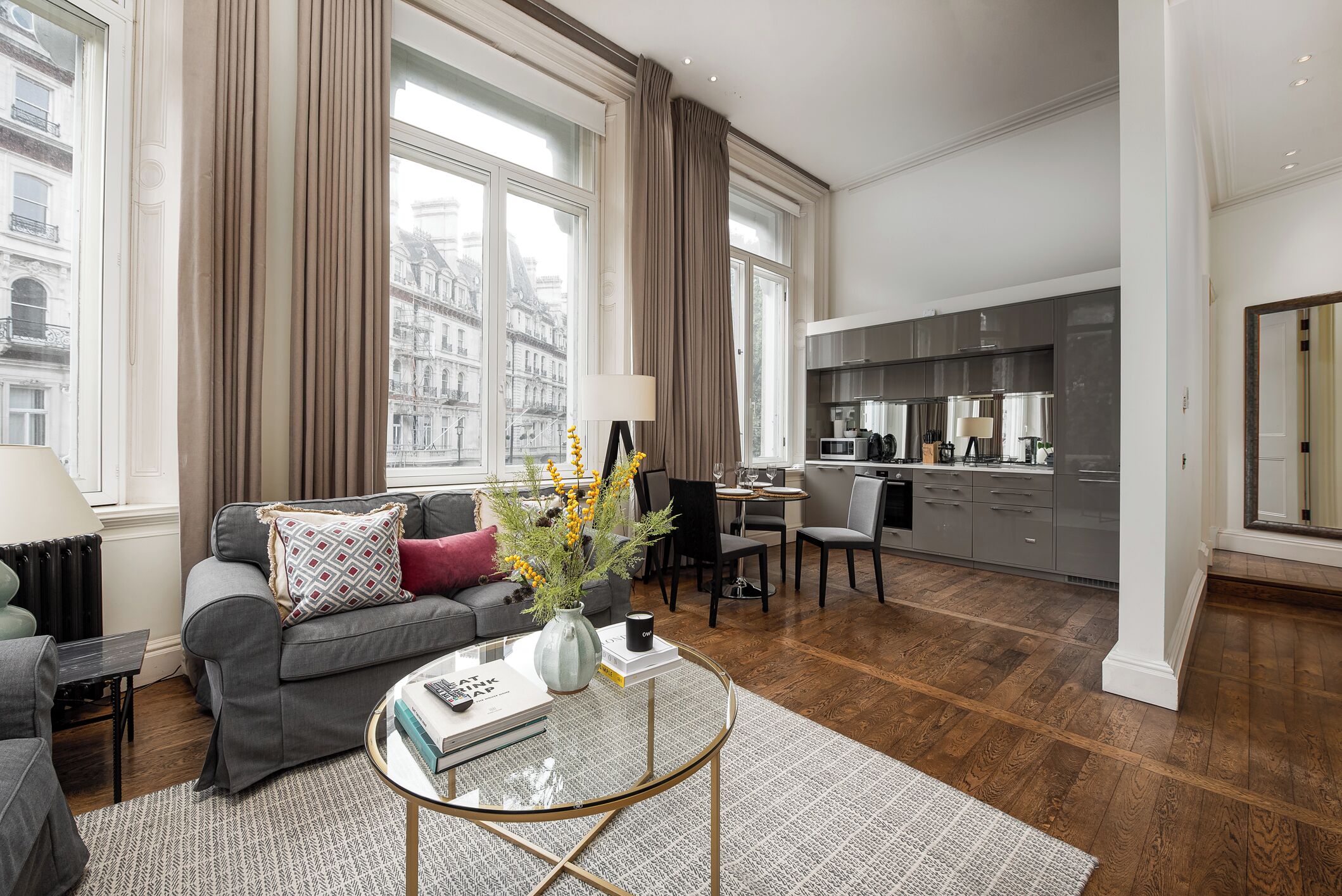 A modern living room with a sofa, a coffee table with books, and a view of the city through large windows.