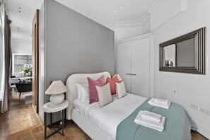 Una habitación de hotel con cama, mesita de noche, lámpara y un espejo en la pared.