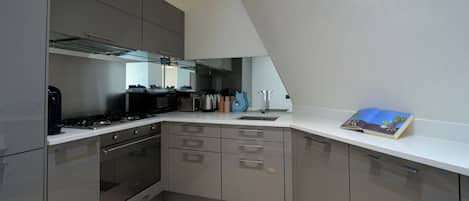 A modern kitchen with built-in appliances, a sink, and a small book on the counter.