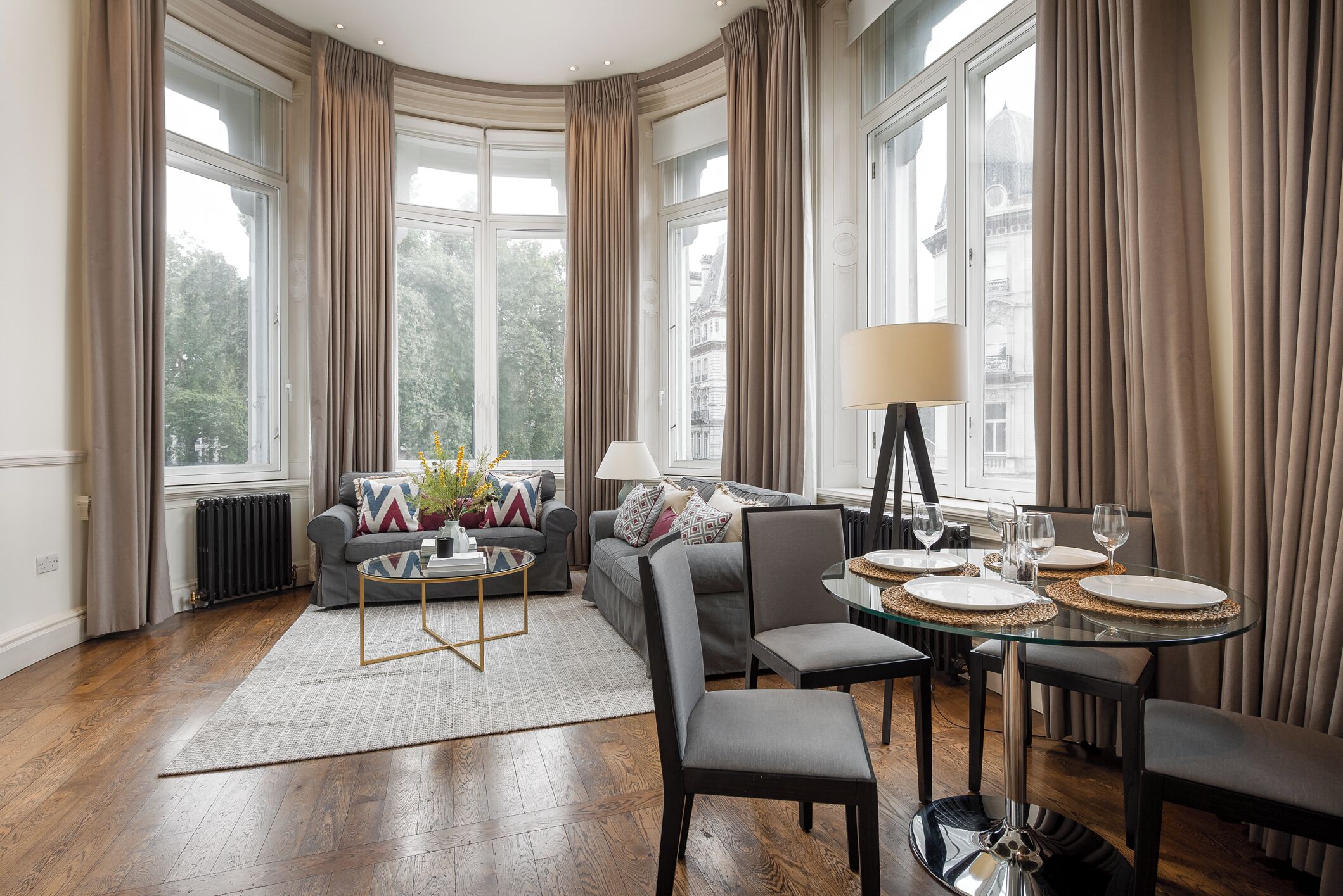 A modern living room with a sofa, coffee table, and dining table set for four.