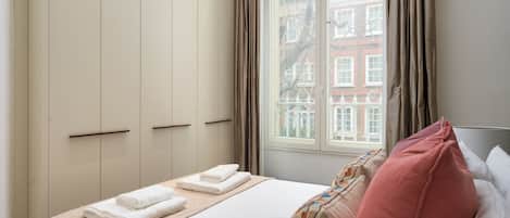Une chambre d’hôtel avec un lit, une fenêtre avec des rideaux et une vue sur les bâtiments environnants.
