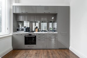 Una cocina moderna con gabinetes grises, un horno Bosch, un microondas y una cafetera.