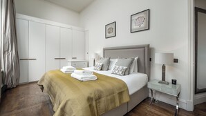 Ein Schlafzimmer mit einem Bett, Nachttischen, einem Kleiderschrank und Bildern an der Wand.