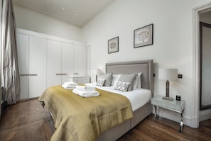 Ein Schlafzimmer mit einem Bett, Nachttischen, einem Kleiderschrank und Bildern an der Wand.