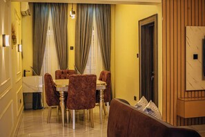A dining area with a table and chairs, a sofa, and a door.