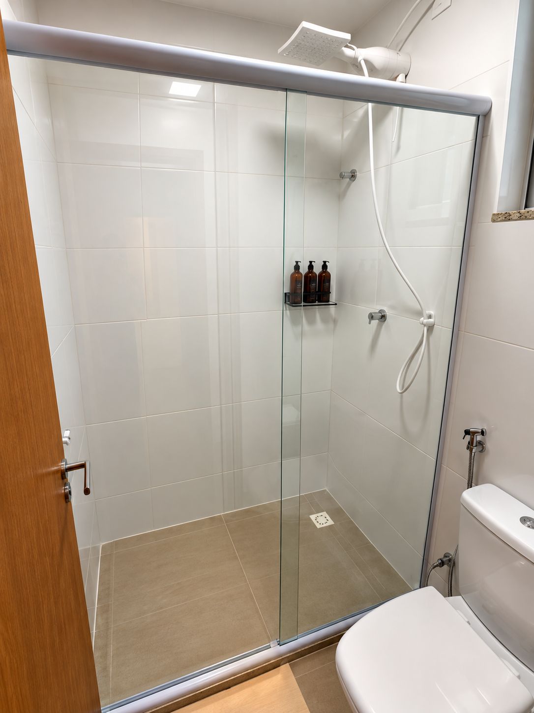 Un espace douche fermé par des parois de verre, avec des toilettes sur le côté droit.
