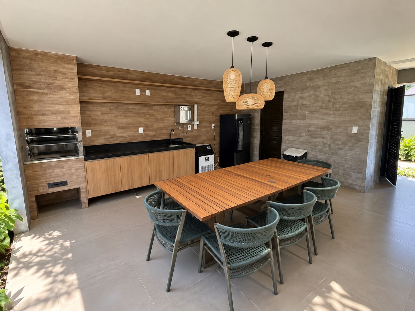 A modern kitchen with built-in appliances, a wooden dining table, and wicker chairs.