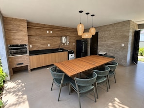 A modern kitchen with built-in appliances, a wooden dining table, and wicker chairs.