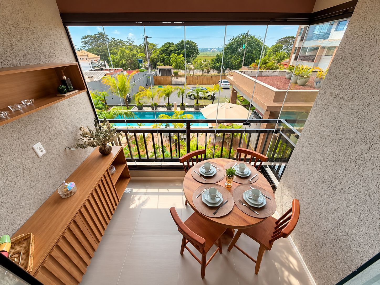 Ein Balkon mit Blick auf einen Swimmingpool und umliegendes Grün.