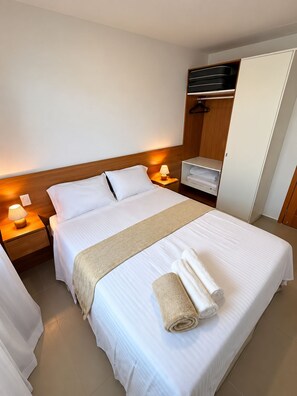 A hotel room with a bed, nightstands, a wardrobe, and a bathroom.