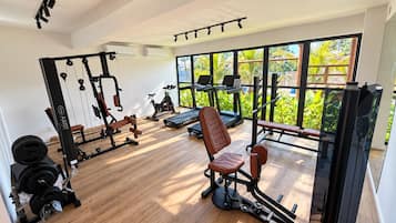Une salle de sport équipée de machines de cardio, d’appareils de musculation et d’un banc.