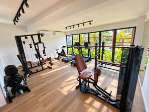 A gym with cardio equipment, weight machines, and a bench.