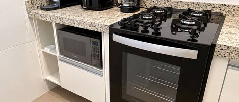 A compact kitchen with a built-in microwave, oven, and gas stove.