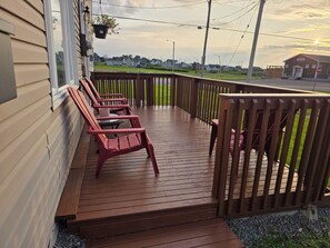 A wooden deck with a railing, a bench, and a hanging planter.