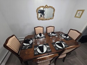 A dining table set for six with chairs, a mirror, and a framed picture on the wall.