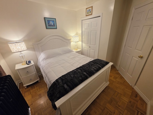 A bedroom with a bed, bedside tables, a wardrobe, and a door.