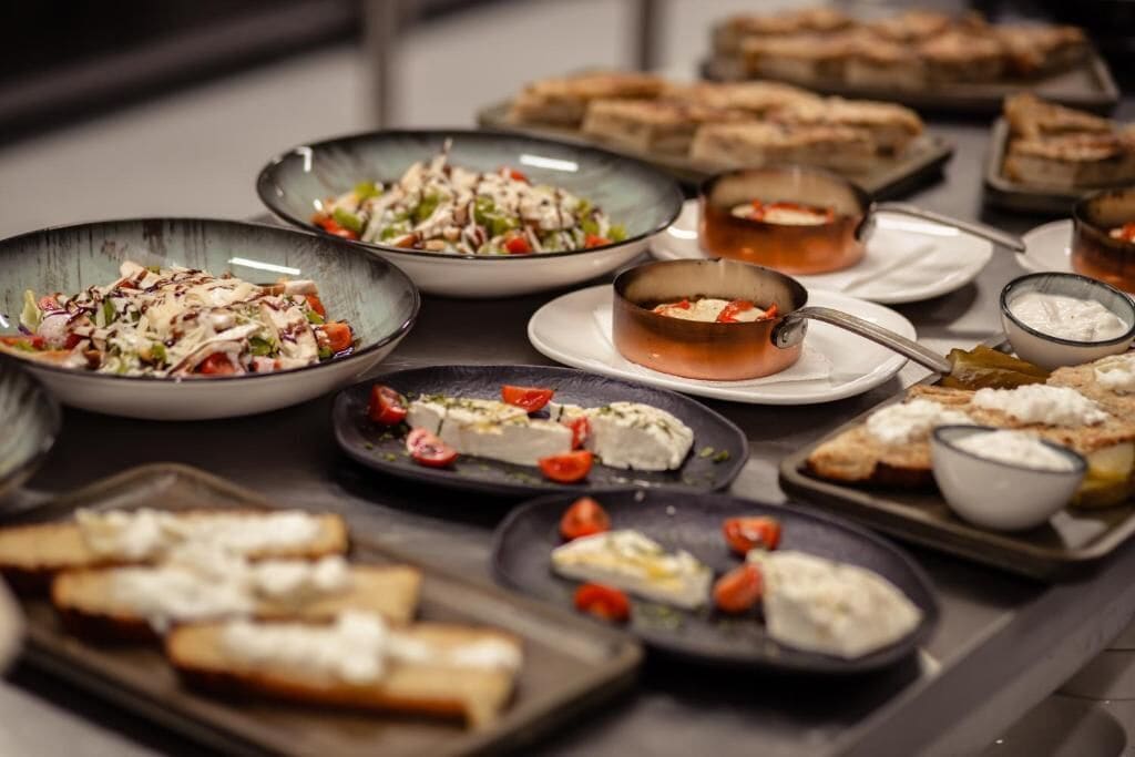 Un buffet proposant une variété de plats, notamment des salades, des fromages et du pain.