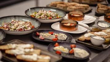 A buffet with various dishes including salads, cheeses, and bread.