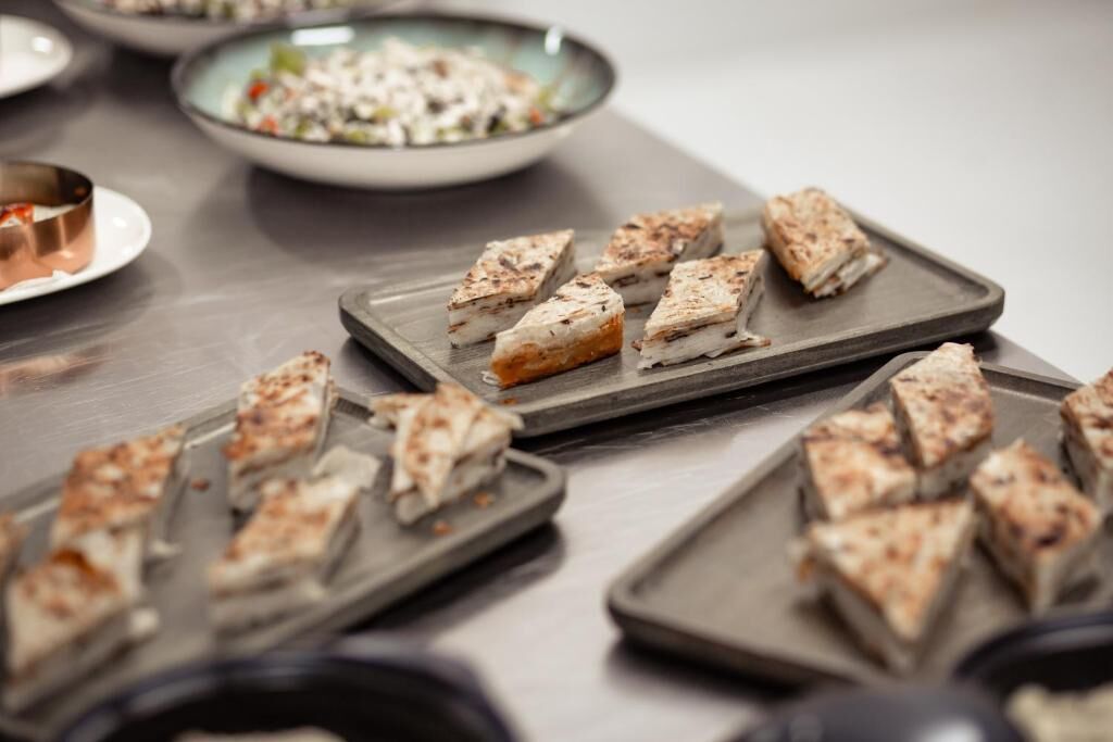 Una mesa con alimentos ordenados, posiblemente aperitivos, en platos rectangulares.